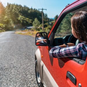 a woman looking outside of her window as she drives