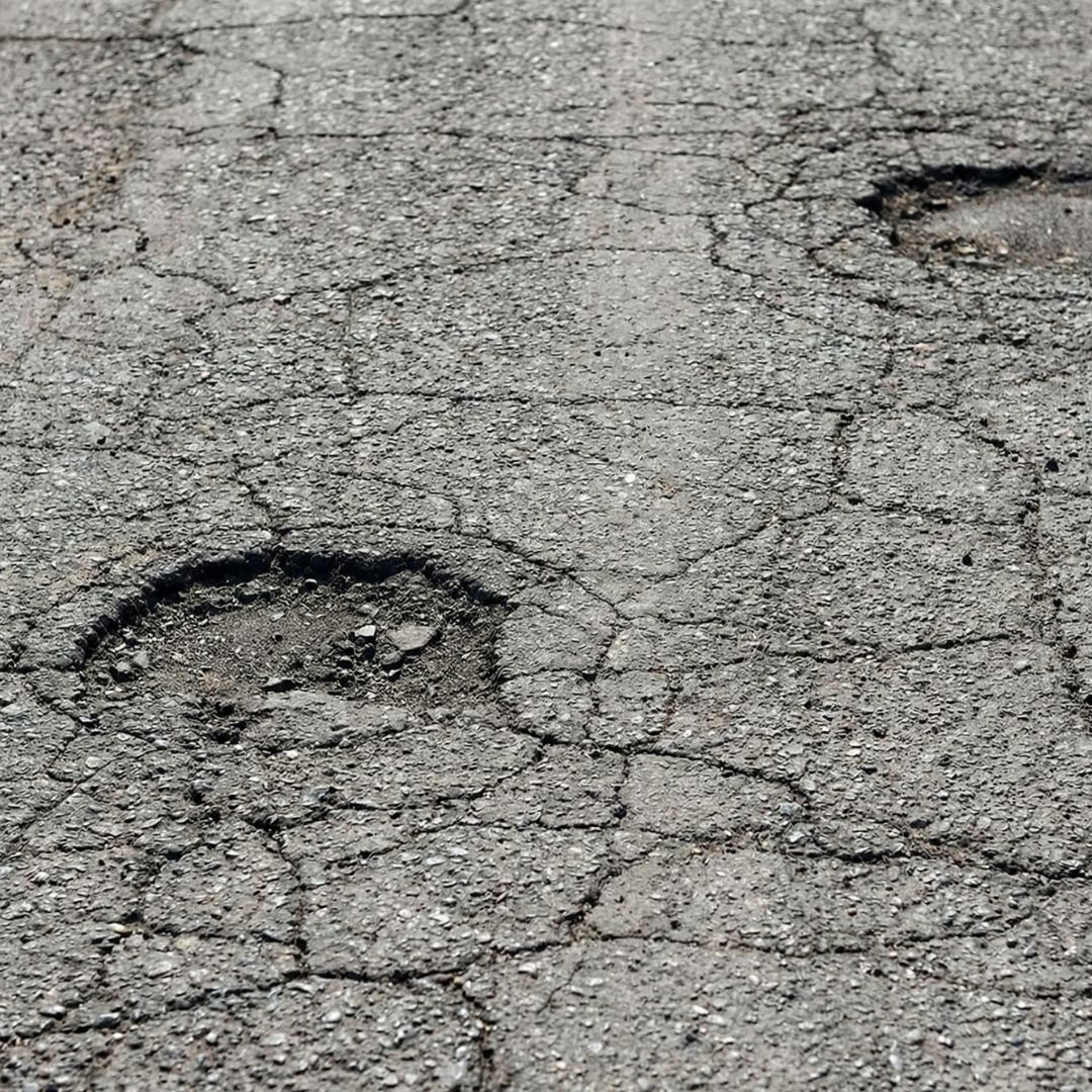 A close-up view of an old asphalt surface showing cracks and wear.