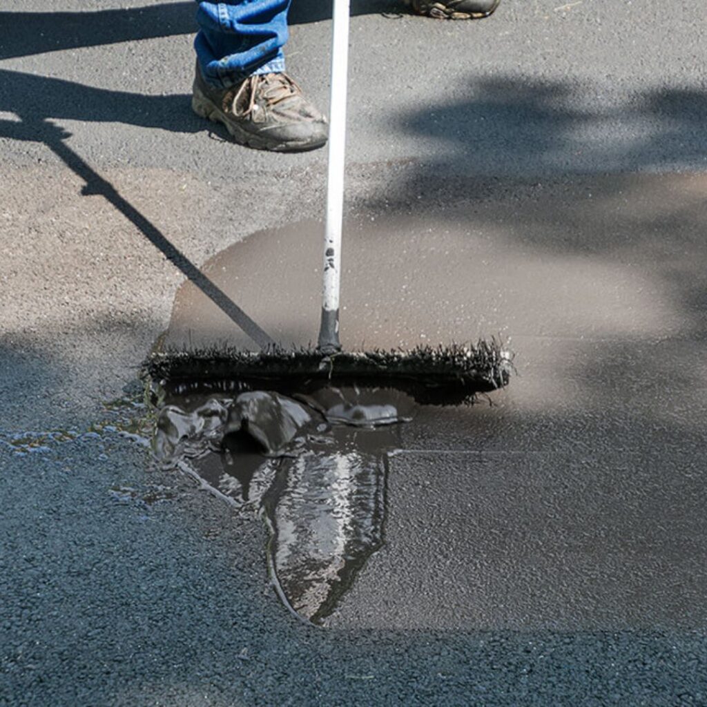 A contractor professionally seal coating a residential driveway.